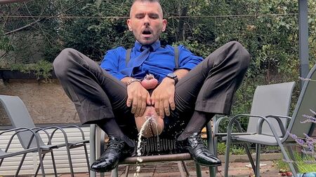 Takım elbiseli, penisi kilitli adam, erkek amıyla oynuyor ve şeffaf çoraplarıyla herkesin içinde işiyor